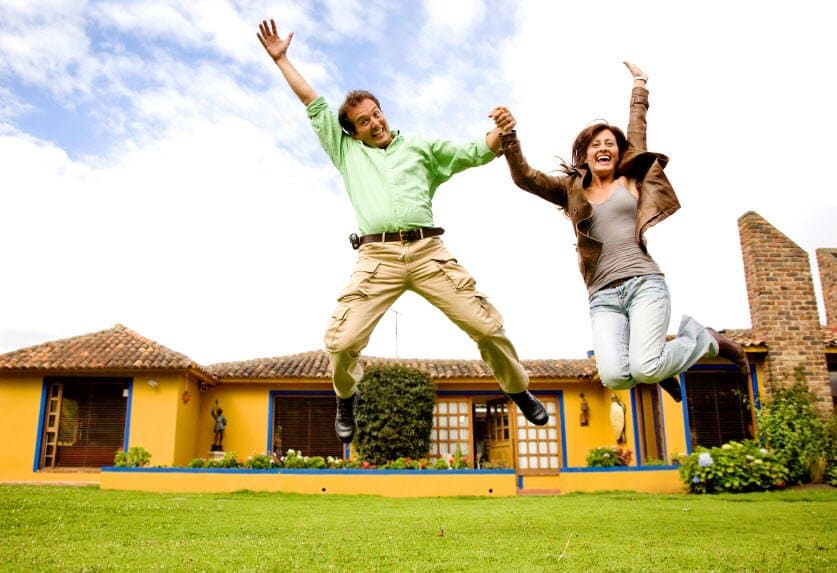 couple jumping in front of house